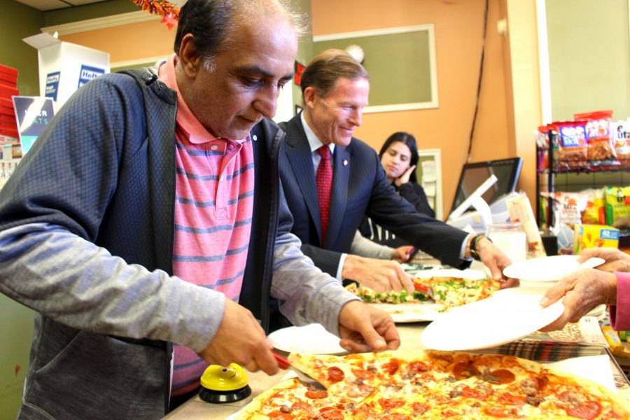 Malik Naveed bin Rehman and United States Senator Richard Blumenthal serve pizzas after Rehman and wife Zahida Altaf spent seven months in sanctuary.