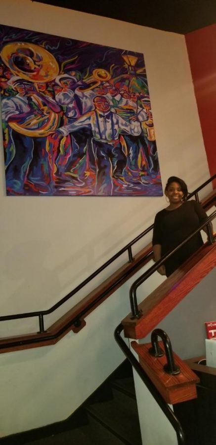 Owner Camille Delices of Tavola 153 in front of artwork she co-painted for the restaurant.