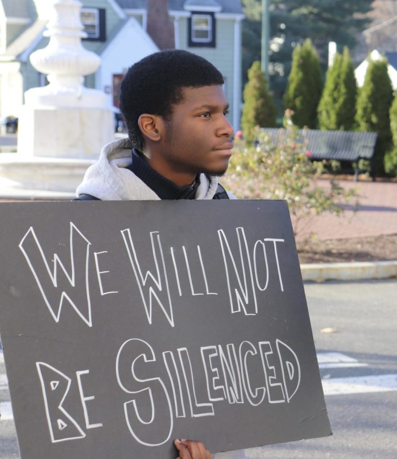 Black student holding up a sign that says, “We Will Not Be Silenced.”